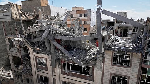 First responders inspect a residential building hit in an earlier U.S.-Israeli strike in Tehran, Friday, March 27, 2026.