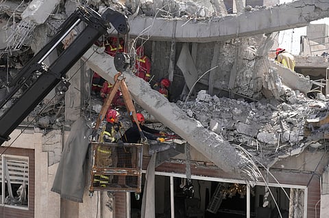 First responders work to remove a body from the rubble of a residential building hit in an overnight U.S.-Israeli strike in Tehran.