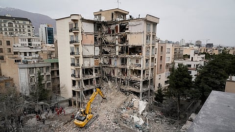 Iranian Red Crescent emergency workers use a bulldozer to clear rubble from a residential building that was hit in an earlier U.S.-Israeli strike in Tehran, Iran, Monday, March 23, 2026.