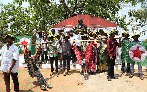 Tribals from Anakapalle district stage a protest by carrying makeshift stretchers (dolis) at the Gandhi statue in Visakhapatnam on Saturday, demanding road connectivity to their hamlets.
