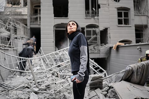 A woman looks up at the site of a strike that hit a residential building amid the U.S.-Israeli military campaign in Tehran, Iran, Saturday, March 28, 2026.