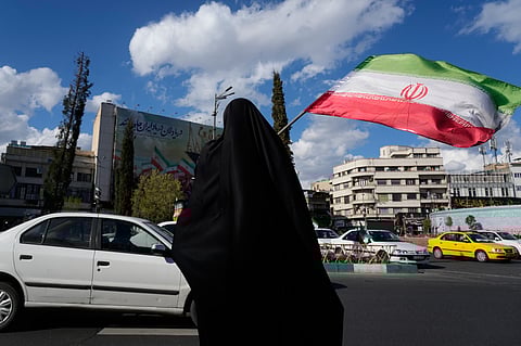 A woman waves an Iranian flag during a campaign in support of the government at the Enqelab-e-Eslami, or Islamic Revolution, square in downtown Tehran, Iran, Monday, March 30, 2026.