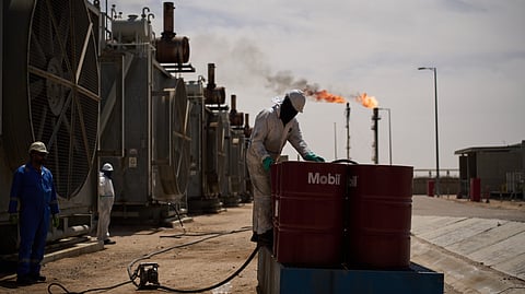 A worker collects engine oil as he works at a degassing station in the Zubair oil field, whose operations have been reduced due to the Middle East war triggered by the US and Israeli attacks on Iran, near Basra, Iraq, Saturday, March 28, 2026.