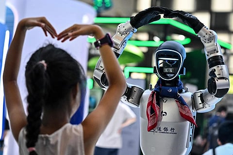 A girl plays with a humanoid robot during the World Artificial Intelligence Conference in Shanghai