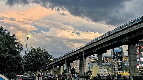 A metro train passes by as rain clouds fill the evening sky in Gurugram on Tuesday.