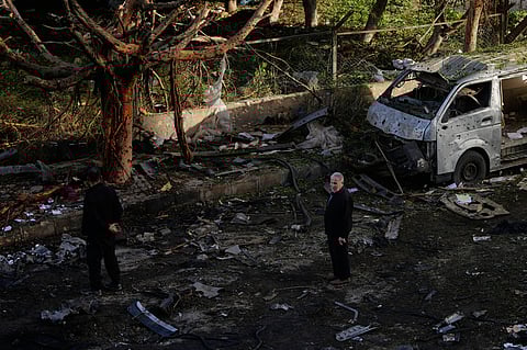 People stand near a damaged van beside scattered debris following an Israeli strike in Beirut, Lebanon, Wednesday, April 1, 2026.