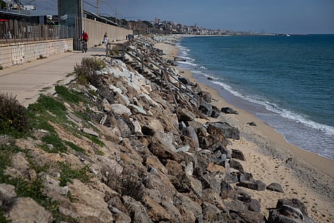 People walk along the rocky seafront promenade at Montgat beach north of Barcelona