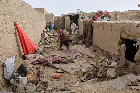 Locals inspect a damaged house following floods, landslides and thunderstorms in Kandahar province, Afghanistan, Sunday, March 29, 2026.