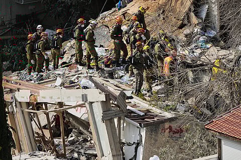 Israeli rescue teams search for missing people amid the rubble of a residential building a day after it was struck by an Iranian missile in Haifa, Israel, Monday, April 6, 2026.