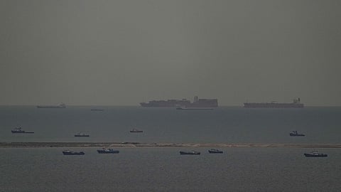 Fishing boats dot the sea as cargo ships, in the background, sail through the Arabian Gulf toward the Strait of Hormuz off the United Arab Emirates, Friday, March 27, 2026.