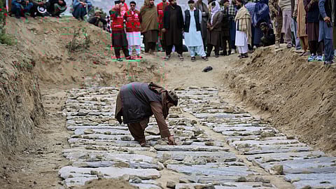 A man places stones on graves during a second mass funeral for victims of an earlier airstrike on a drug rehabilitation center, in Kabul, Afghanistan, Thursday, March 26, 2026.