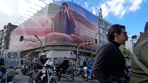People drive their motorbikes past a billboard that shows a graphic depicting Iran's Supreme Leader Ayatollah Mojtaba Khamenei in downtown Tehran, Iran, Monday, April 6, 2026.