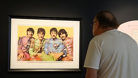A visitor looks at a signed frame of 'The Beatles'