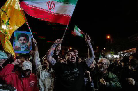 Pro-government demonstrators chant slogans as they hold Iranian flags and a poster of the Supreme Leader Ayatollah Mojtaba Khamenei in a gathering after announcement of a two-week ceasefire in the war with the United States and Israel, at the Enqelab-e-Eslami, or Islamic Revolution, Square, in Tehran, Iran, Wednesday, April 8, 2026.