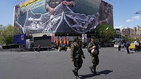 Two police officers walk in front of an anti-US billboard depicting American aircraft being caught by Iranian armed forces in a fishing net beneath the words in Farsi, "The Strait of Hormuz will remain closed. The entire Persian Gulf is our hunting ground," in Tehran, Iran, Sunday, April 5, 2026.