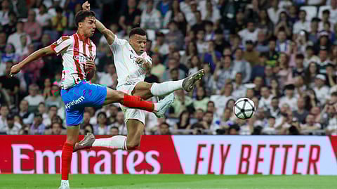 Real Madrid's Kylian Mbappe (R) is challenged by Girona's defender #12 Vitor Reis during the Spanish league football match between Real Madrid CF and Girona FC at the Santiago Bernabeu stadium in Madrid on April 10, 2026.