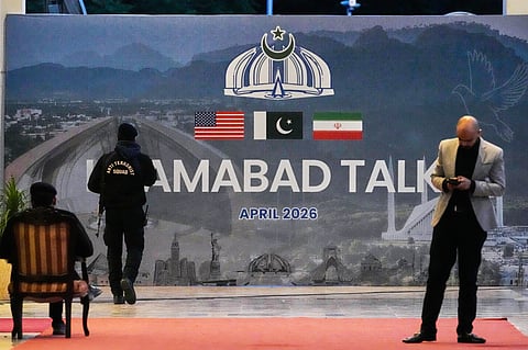 A security guard walks past a billboard of the U.S. Iran talks outside a media center set up for the coverage of the U.S. Iran official meeting, in Islamabad, Pakistan, Sunday, April 12, 2026.
