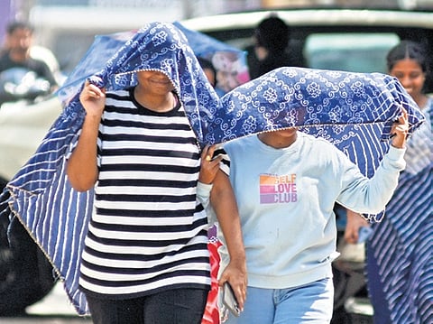 People cover themselves with dupatta as they go out on a sunny afternoon in Vijayawada.