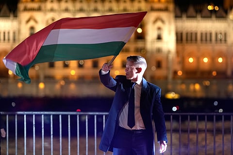 Peter Magyar, the leader of the opposition Tisza party waves a national flag after a parliamentary election in Budapest, Hungary, Sunday, April 12, 2026.