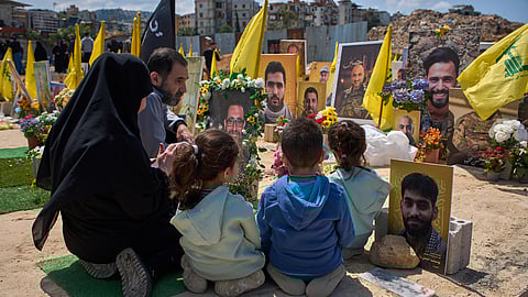 Family members pray at the grave of a relative buried alongside Hezbollah fighters killed in Israeli strikes in a cemetery in Choueifat, Lebanon, on Monday, April 13, 2026.