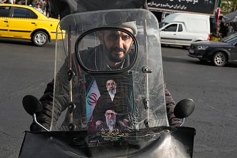 A man drives his motorbike with a poster on its windshield depicting Iran’s Supreme Leader Ayatollah Mojtaba Khamenei, top, and his father, the slain Supreme Leader Ayatollah Ali Khamenei, who was killed in the U.S. and Israel strikes on Feb. 28, in downtown Tehran, Iran, Monday, April 13, 2026.