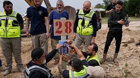 Paramedics attach a portrait over the grave of Ghadir Baalbaki, 19, who was killed on Tuesday in an Israeli airstrike, at a temporary mass grave in the southern port city of Tyre, Lebanon, Wednesday, April 15, 2026.