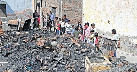 People look at charred remains after a fire broke out in Rohini