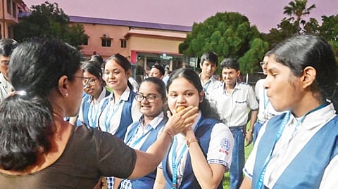 A teacher of BJEM School offering sweets to successful students in Bhubaneswar on Wednesday | express