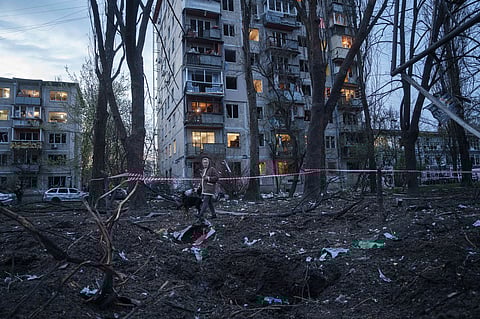 A woman with a dog walks among the rubble of a house damaged after a Russian strike on residential area in Kyiv, Ukraine, on Thursday, April 16, 2026.