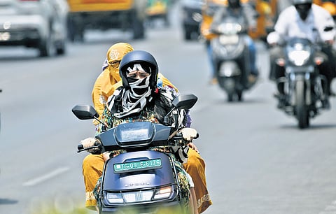 Commuters shield themselves with cotton scarves while travelling on a two-wheeler in Hyderabad on Thursday