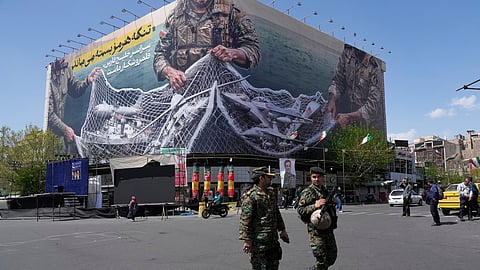Two police officers walk in front of an anti-U.S. billboard depicting American aircraft being caught by Iranian armed forces in a fishing net beneath the words in Farsi, "The Strait of Hormuz will remain closed, The entire Persian Gulf is our hunting ground," in Tehran, Iran, Sunday, April 5, 2026.