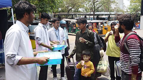 Members of the Satya Sai Seva Samithi, along with dental students, distribute buttermilk to passengers at JBS Bus Station, offering relief from the scorching summer heat.
