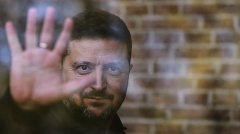 Ukraine's President Volodymyr Zelenskyy waves from behind a glass window after he received the Freedom Medal of the International Four Freedoms Award during a ceremony in Middelburg, Netherlands, Thursday, April 16, 2026.