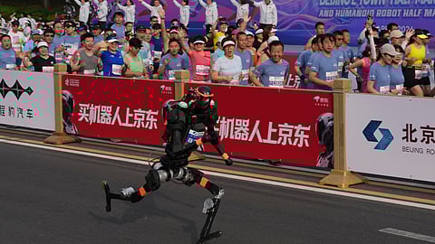 A robot starts off next to human marathon runners for the Beijing E-Town Half Marathon and Humanoid Half Marathon held on the outskirts of Beijing on Sunday April 19, 2026.