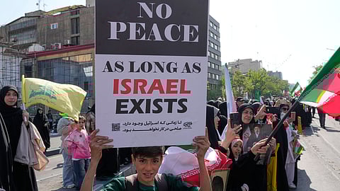 A boy holds up an anti-Israeli placard during a state-organized rally in support of the supreme leader marking National Girl's Day in Tehran, Iran, Friday, April 17, 2026.