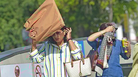 People using scarf, Cap and Umbrella to cover face for protection against sun as Temperature increases close to 40 degree in Delhi.