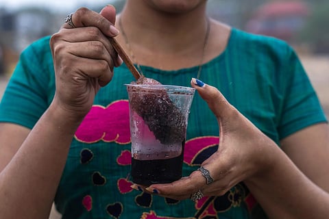 A girl hold a plastic glass as she prepares to drink Shaved ice at Juhu beach in Mumbai, India, on June 30, 2022.