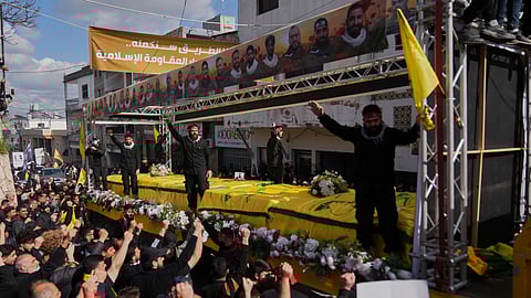 Coffins of Hezbollah fighters killed before the ceasefire in the war between Hezbollah and Israel are carried on a truck past mourners during a mass funeral procession in the southern village of Kfar Sir, Lebanon, Tuesday, April 21, 2026.