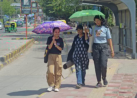 People use umbrellas as temperature rises in Delhi on Tuesday.
