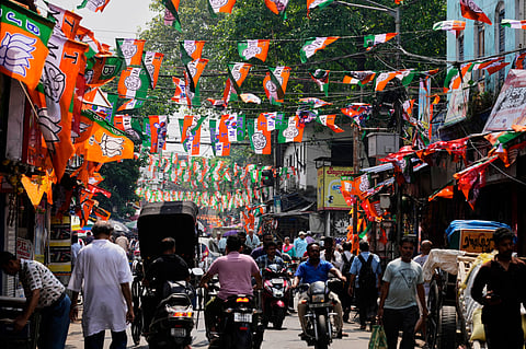 Commuters pass through a busy street decorated with the flags of Bharatiya Janata Party and Trinamool Congress party ahead of the West Bengal state Legislative Assembly elections in Kolkata, Saturday, April 18, 2026.