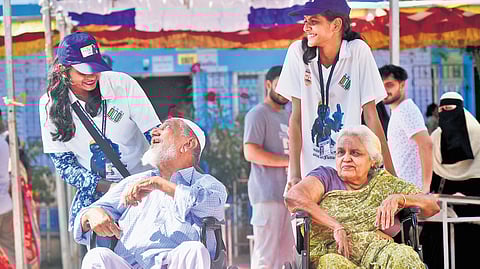 Hand of help: Elderly voters share a light moment with volunteers at a polling station in Chennai.