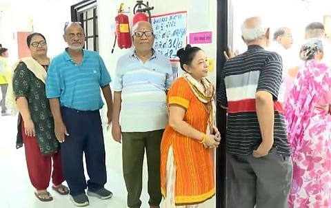 People wait in queue to cast their votes in a polling booth in Ahmedabad.