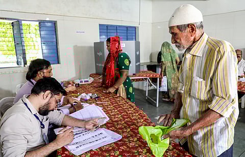 : A polling official checks details before people cast their votes for the municipal corporation elections, in Rajkot, Sunday, April 26, 2026.