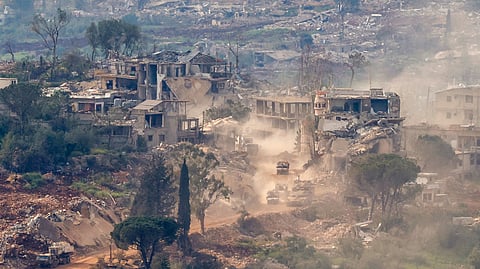 This photograph taken from the northern Israel shows Israeli tanks and military vehicles driving along the road between destroyed houses in southern Lebanon near the border with Israel, on April 25, 2026.