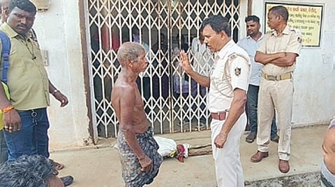 Policemen speak to Jitu Munda in front of the Odisha Gramya Bank branch