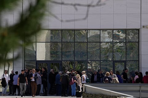 People gather outside a courthouse after a gunman opened fire leaving several people wounded in Athens, Tuesday, April 28, 2026.