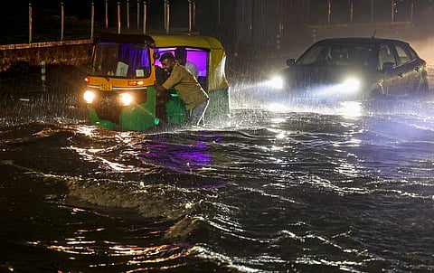 Commuters make their way through a waterlogged Mysore Road following heavy rain, in Bengaluru, Wednesday, April 29, 2026.