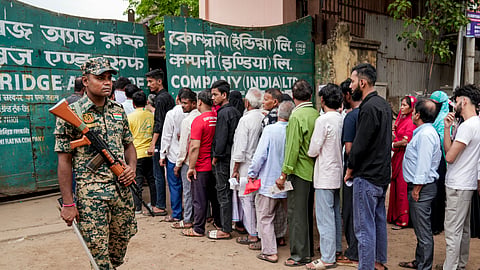 A security personnel keeps vigil as people wait in queues before casting their votes in the second and final phase of the West Bengal Assembly elections, at a polling station in Howrah, Wednesday, April 29, 2026.