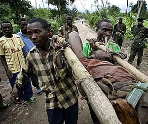 Rebel soldiers loyal to Gen Laurent Nkunda carry a soldier wounded in the village of Kiwanja in eastern DR Congo. AP