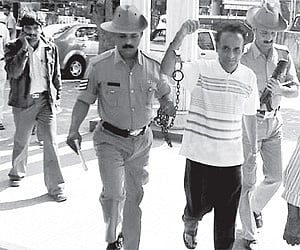 Chitra Publications chairman and journalist B V Seetharam being brought handcuffed to the Udupi court on Monday.